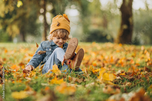 Cute boy playing with leaves in autumn park
