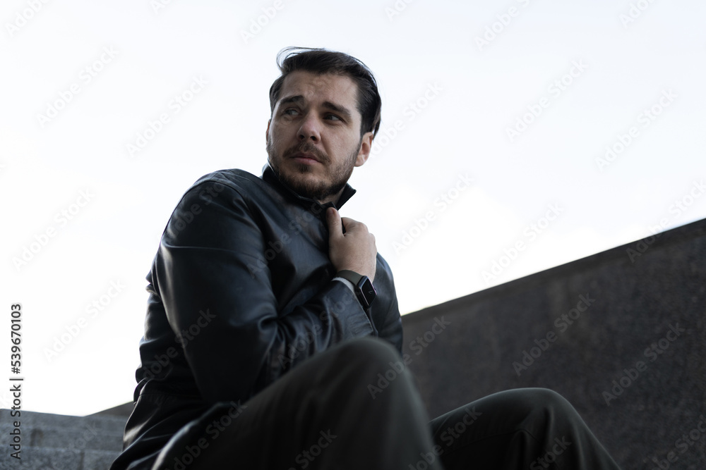 Obraz premium upset man in deep depression sits on black steps near gray wall