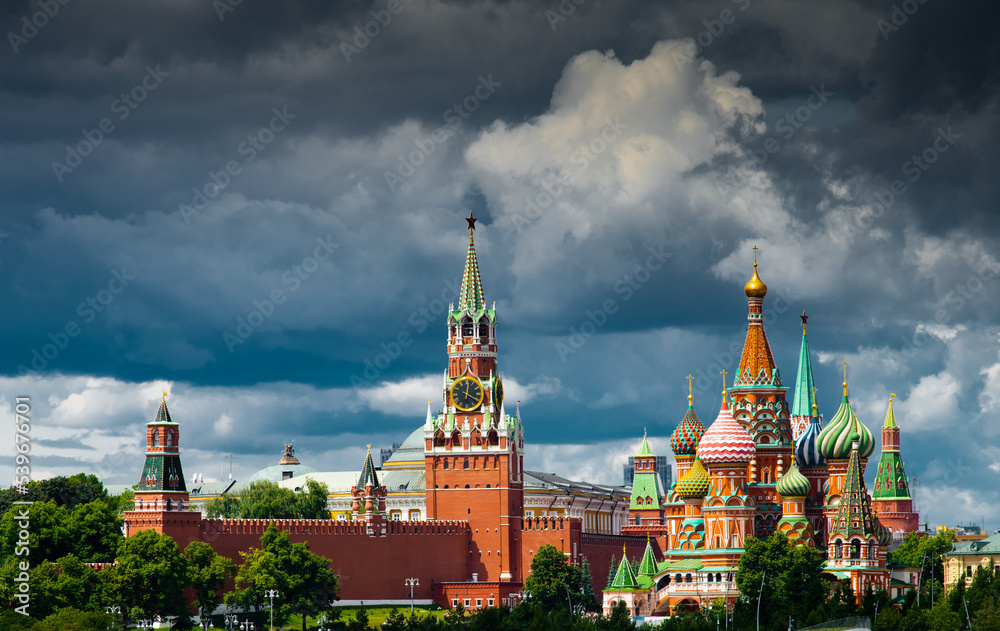 Spasskaya Tower of Moscow Kremlin and Cathedral of Vasily the Blessed (Saint Basil's Cathedral) on Red Square in summer day. Black clouds before the rain. Panoramic view. Moscow. Russia