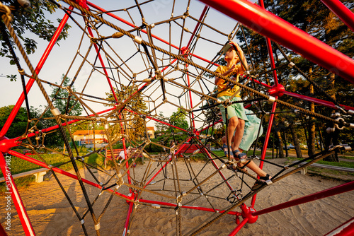 Kids play in rope polyhedron climb at playground outdoor.