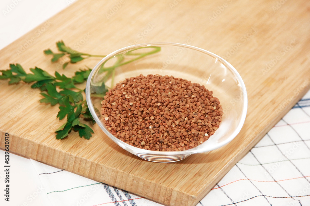 small grains of natural brown buckwheat in a transparent glass plate small grains of natural brown buckwheat in a transparent glass plate