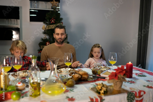 Praying before Christmas dinner at the table full of food