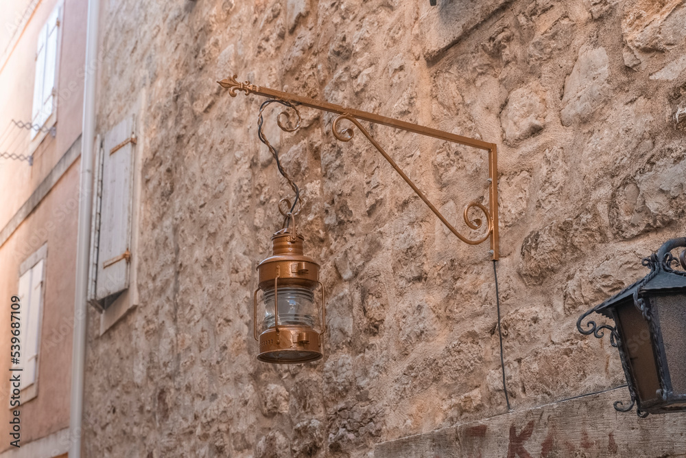 an old street lamp attached to the stone wall of an old building. Old lighting fixtures. An antique lamp an old street lamp attached to the stone wall of an old building. Old lighting fixtures. An antique lamp