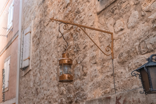 Fototapeta Naklejka Na Ścianę i Meble -  an old street lamp attached to the stone wall of an old building. Old lighting fixtures. An antique lamp