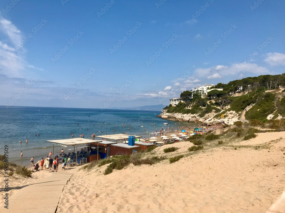 Salou, Spain, June 2019 - A group of people sitting on a sandy beach