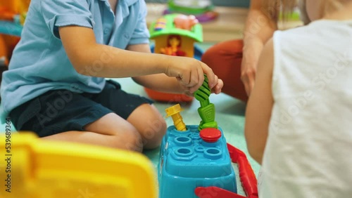 Group of small kids in nursery playing with colorful educational toys. Creative playtime with teacher. Horizontal indoor shot . High quality 4k footage