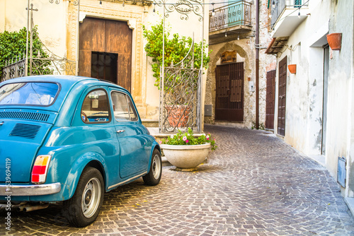a small old blue car in the narrow streets of the historic old town. cobbled streets and old buildings photo