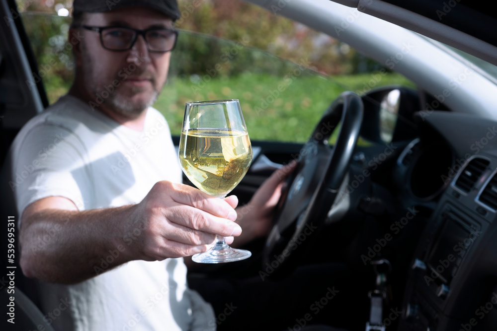 A man with a glass of wine driving a car. A man with a glass of wine driving a car.