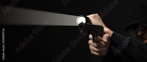 Professional security guard or policeman with flashlight and gun in dark room