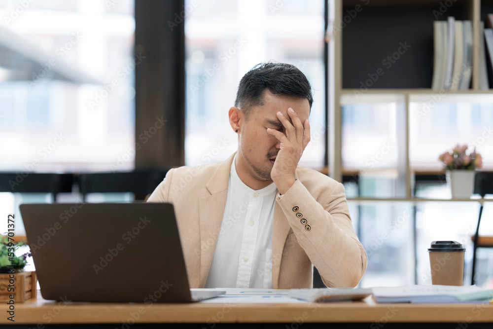 Stressed Asian businessman worry with many document on desk at office