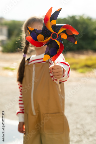 A girl is holding an orange pinwheel in autumn photo