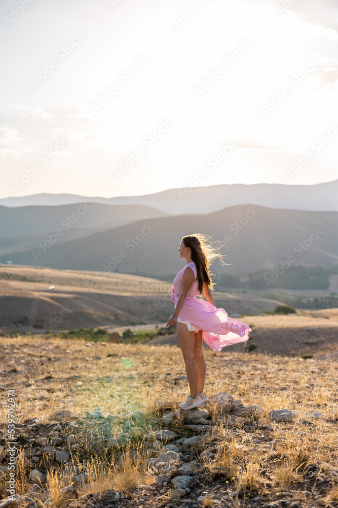 young girl in a pink dress enjoys a walk in the mountains.