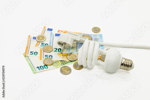Light bulb, electric plug, and the euro money banknotes. Concept of expensive electricity costs