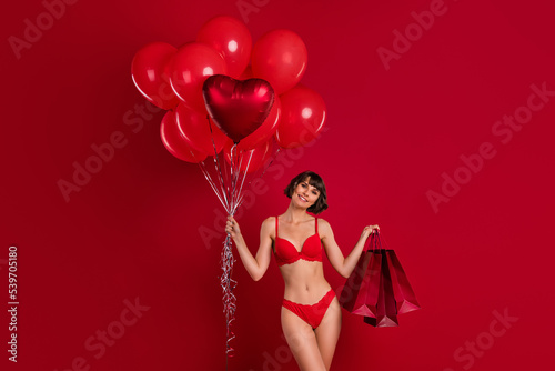 Portrait of attractive nude cheery fit girl holding festal air balls gift present surprise isolated over bright red color background