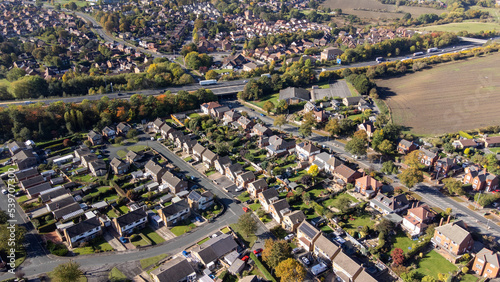 Aerial drone photo of the British town of Wakefield in West Yorkshire, England showing typical British UK housing estates and roads near a farmers field and the motorway, filmed in the autumn time.