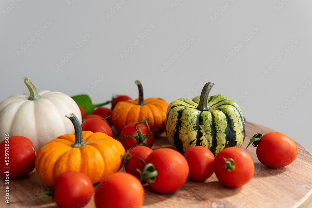 colorful pumpkins with tomatoes on a wooden table with a blurred background. autumn harvest atmosphere. colorful pumpkins with tomatoes on a wooden table with a blurred background. autumn harvest atmosphere.
