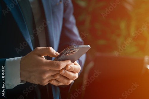 Businessman in suit with mobile phone in hands. Man typing message, using social net. Checking news. Making business meeting. Modern office.General manager,ceo.Calling to partner.Planning working day
