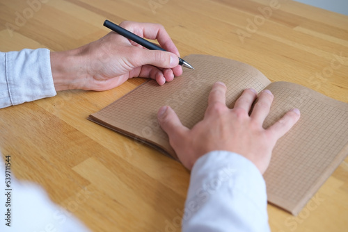 Close up of a person writing on vintage paper of kraft notebook