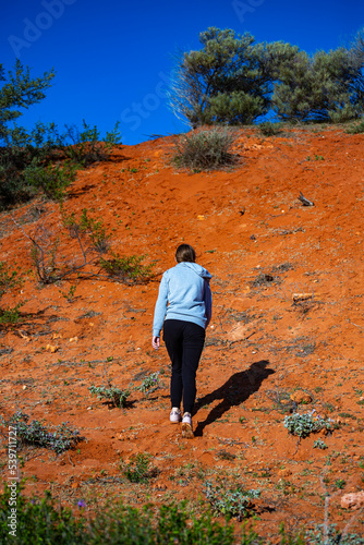 long-haired girl hiking in australian red sand desert; terra rosa in francois peron national park, shark bay, western australia photo