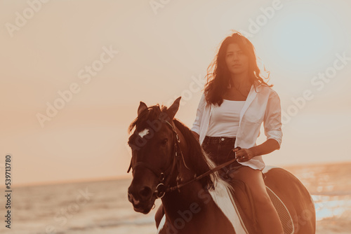 Woman in summer clothes enjoys riding a horse on a beautiful sandy beach at sunset. Selective focus  © .shock