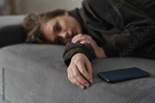 Fotografiet Caucasian woman with mental problem lying down with mobile phone on couch