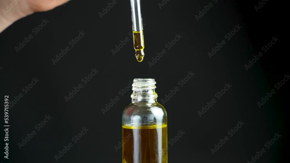 Natural oil for the care of eyelashes, eyebrows, facial skin drips into a glass jar of pipette