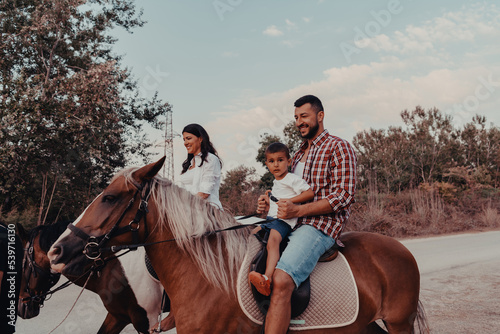 The family spends time with their children while riding horses together on a sandy beach. Selective focus 
