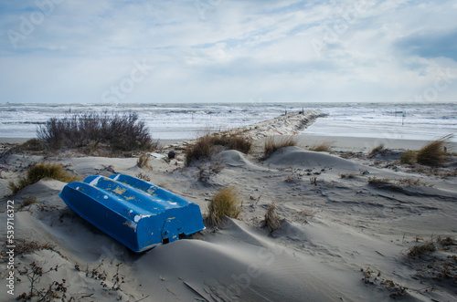 Una piccola barca blu messa al riparo sulle dune  dell'isola di Pellestrina, in una giornata invernale
 photo