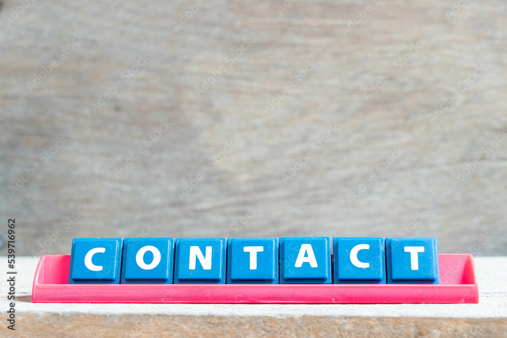 Obraz premium Tile alphabet letter with word contact in red color rack on wood background