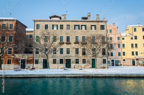 Un canale di Venezia con le barche ve il marciapiede coperto dalla neve