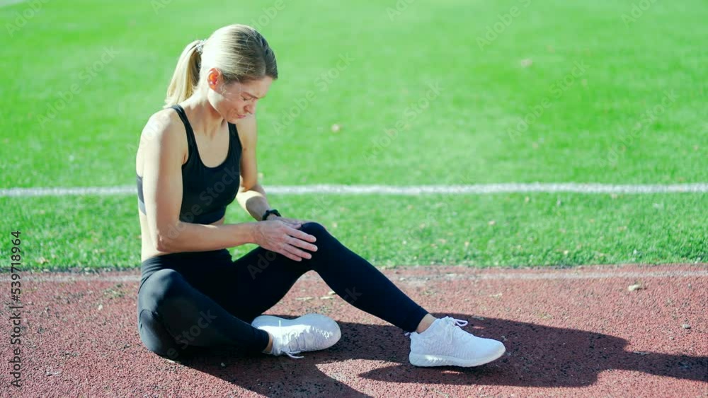 runner athlete with muscle pain sitting on the track of stadium Woman