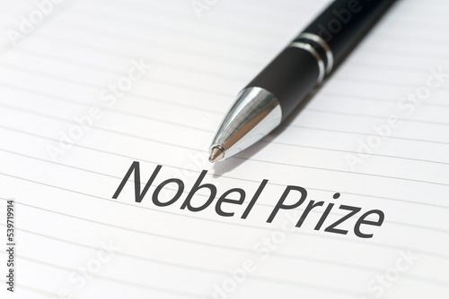 The inscription NOBEL PRIZE on a white sheet notebook.Nobel prize in literature. A pen is lying nearby.White background.Selective focus,close-up.