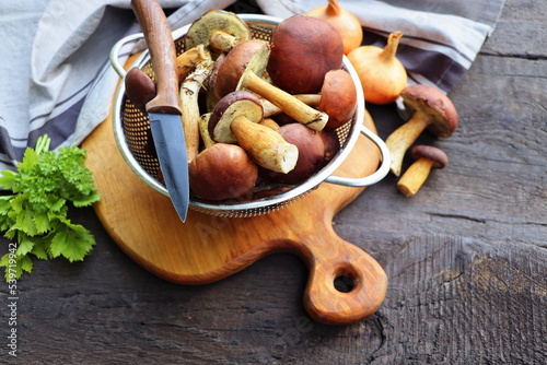 Forest boletus mushrooms on rustic wooden background and a wooden cutting board