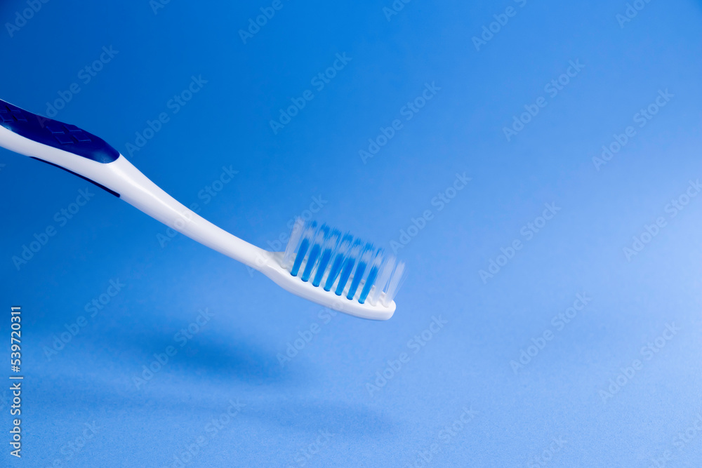 A toothbrush has blue bristles on blue background A toothbrush has blue bristles on blue background