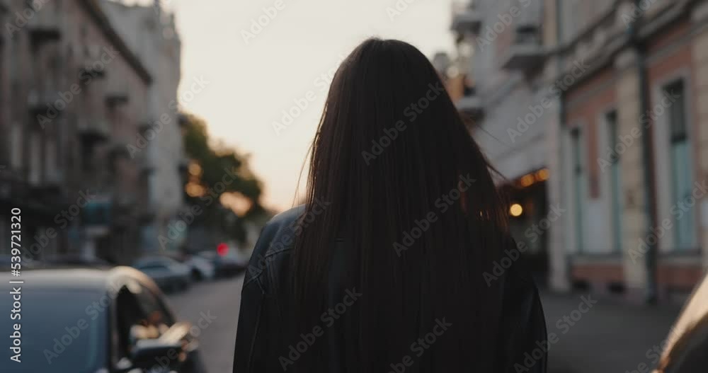 Charming woman walking at the city street turning face, slow motion, back view Charming woman walking at the city street turning face, slow motion, back view