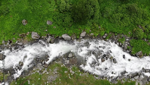 River, top view. Water stream running through stone boulders river in a green valley. Wild mountain river water splashing in summer day