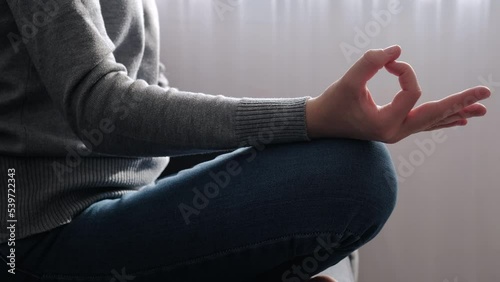 Close up of hand of young female sitting on comfy couch lotus pose, enjoy meditation do yoga exercise in living room at home. No stress, healthy habit, mindfulness lifestyle, anxiety relief concept photo