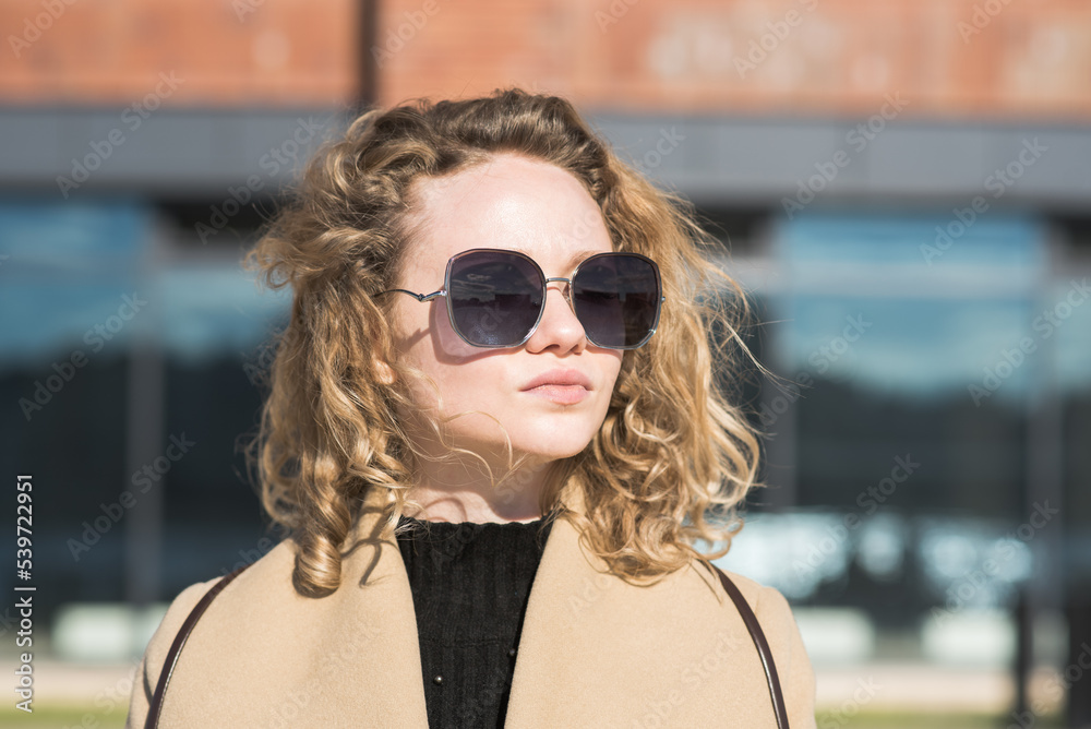 Portrait of a young Caucasian girl in a coat and sunglasses in the city on an autumn day. Portrait of a young Caucasian girl in a coat and sunglasses in the city on an autumn day.