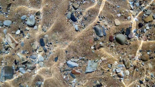 View into the sea with waving bottom with sand and stones. Underwater view of sea bottom on the beach.