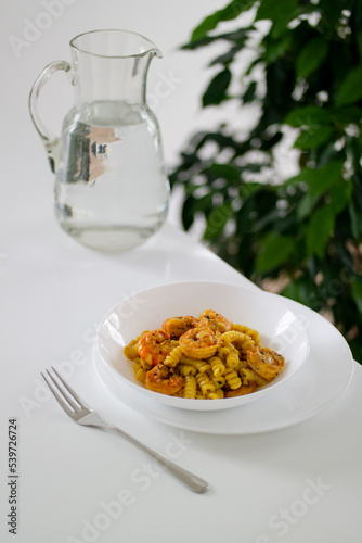 Italian pasta with shrimp and turmeric on a white table in a white plate