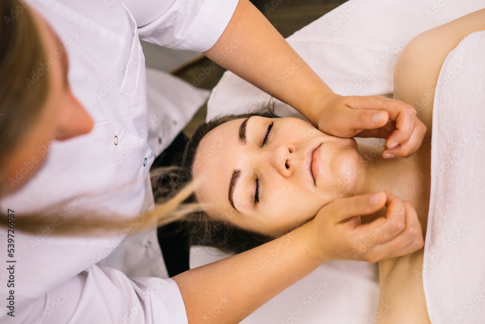 Woman receiving facial massage in beauty salon.Beauty and skincare concept with a beautiful woman. Middle aged female relaxed with massage for facial lifting