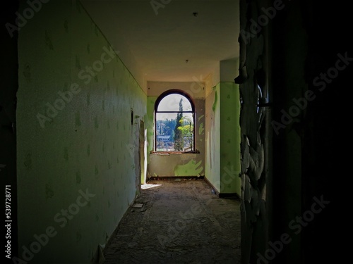 Abandoned hotel room with green wallpaper and broken floor