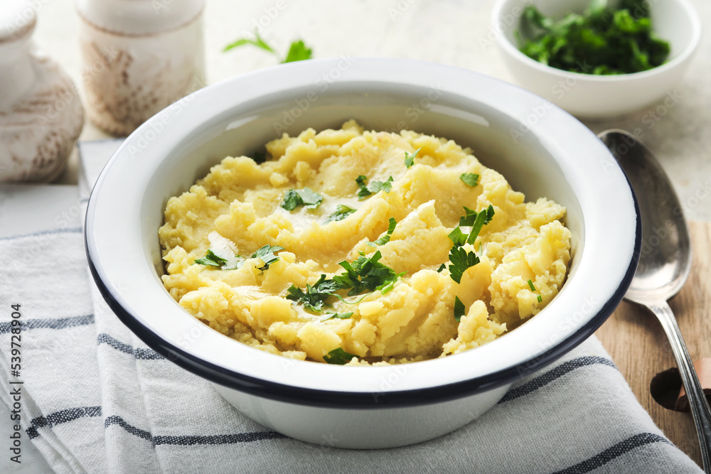 Mashed potatoes. Hot mashed potatoes with butter, fresh parsley herbs and pepper in bowl on slate, stone or concrete backgrounds. Delicious creamy mashed potatoes. Top view. Mashed potatoes. Hot mashed potatoes with butter, fresh parsley herbs and pepper in bowl on slate, stone or concrete backgrounds. Delicious creamy mashed potatoes. Top view.