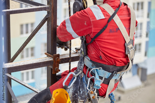 A specialist repairs an antenna on the roof. Rope access