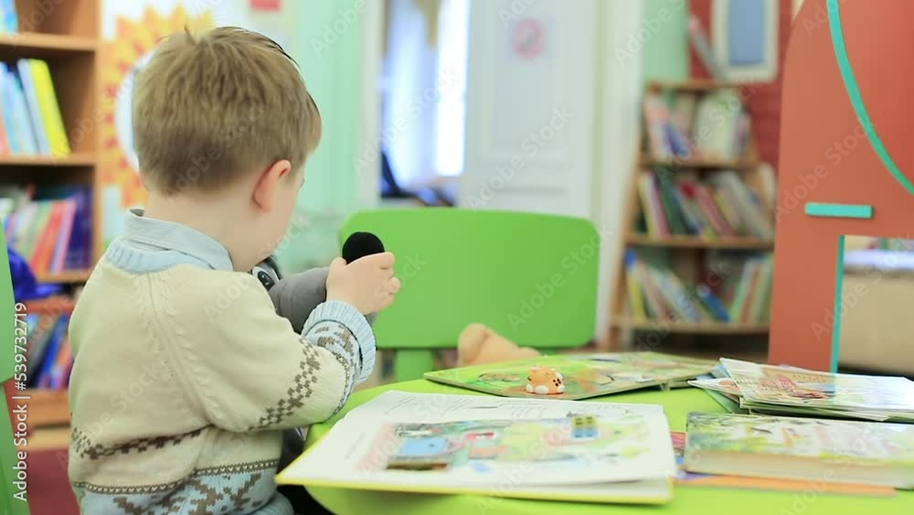 A child learns to read while sitting in a room with books A child learns to read while sitting in a room with books