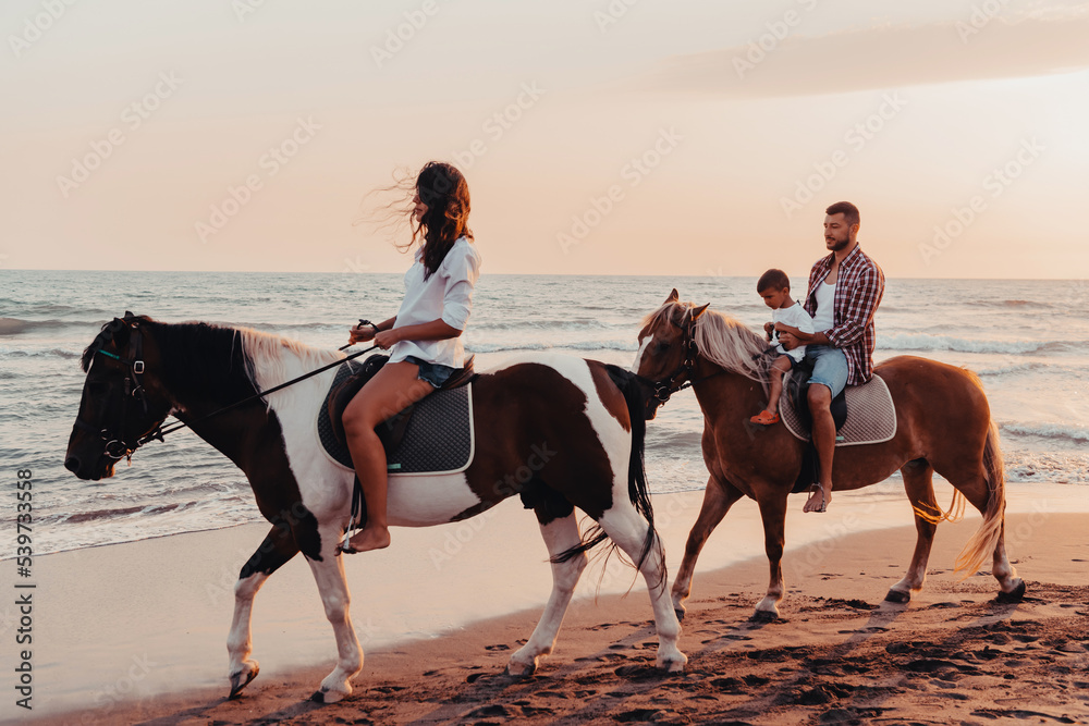 The family spends time with their children while riding horses together on a sandy beach. Selective focus The family spends time with their children while riding horses together on a sandy beach. Selective focus