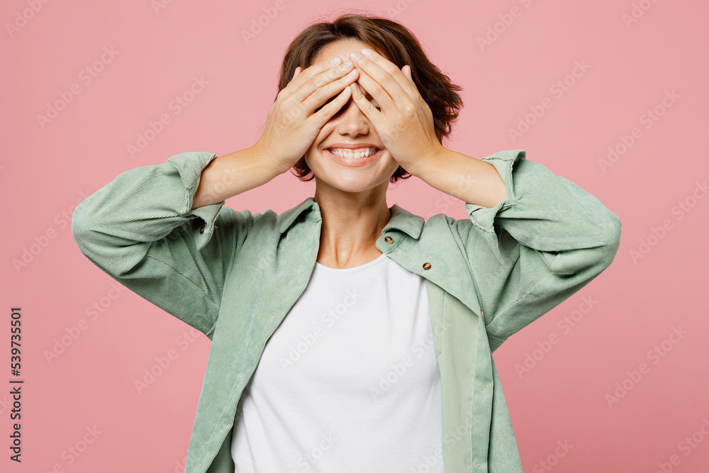 Young satisfied amazed happy woman wear green shirt white t-shirt cover eyes with hands like waiting special moment or surpirse isolated on plain pastel light pink background People lifestyle concept Young satisfied amazed happy woman wear green shirt white t-shirt cover eyes with hands like waiting special moment or surpirse isolated on plain pastel light pink background People lifestyle concept