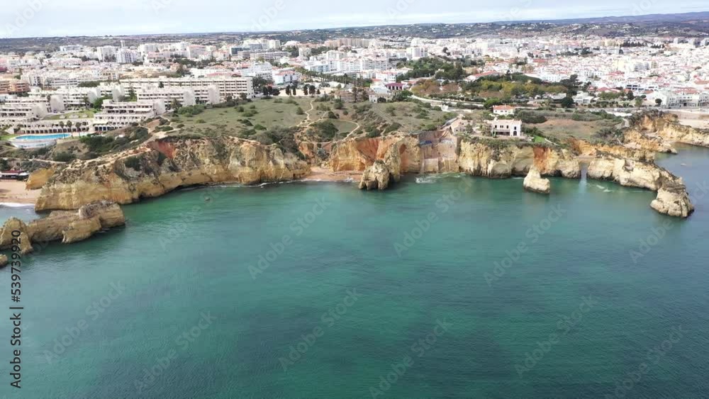 Lagos city situated in south of Portugal - Algarve. Touristic travel destination, famous for the rock formations and caves. Tourist cruise boats. Portuguese landscape. Drone forward and tilt down Lagos city situated in south of Portugal - Algarve. Touristic travel destination, famous for the rock formations and caves. Tourist cruise boats. Portuguese landscape. Drone forward and tilt down