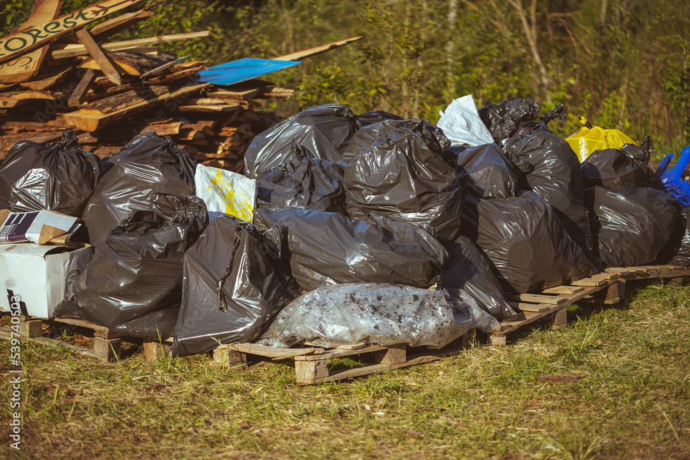 black plastic bags with garbage on wooden palettes. Trash after festivals and celebrations