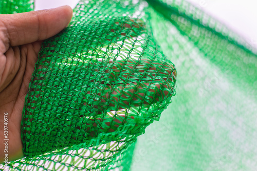 Green shading net pattern texture. Used in gardening, nurseries, agriculture. Texture, weave pattern details close up.	